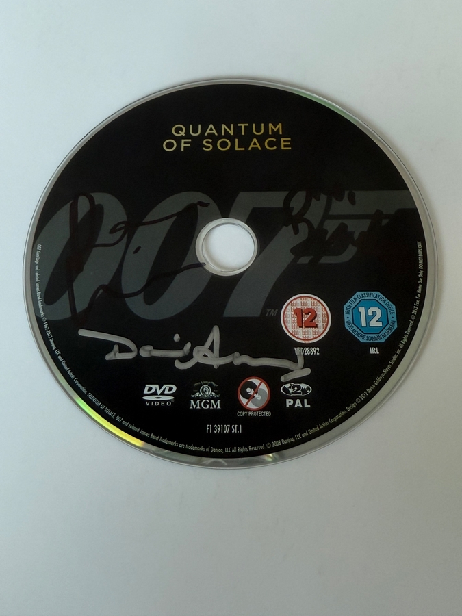 Quantum of Solace DVD disc, signed by Judi Dench, David Arnold  and one other. Disc only